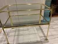 Front-facing view of two-tier side table showing brass frame and clear glass shelves