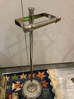 Full view of the vintage metal paper roll holder showing the entire stand, base, and paper rod.