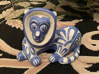 Front view of the vintage stylized lion pottery sculpture showing blue floral and geometric patterns on white background.