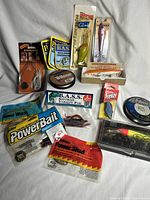Full overview of lot with all items laid out showing variety of fishing lures, fishing lines, B.A.S.S stickers and patch.