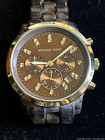 Front view showing round sable brown dial with crystal markers, chronograph subdials, and tortoiseshell style band.