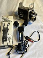 Photo showing vintage stereo electret condenser microphone with box and Kodak Brownie cine camera together on surface