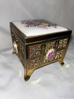 Side and angled view of vintage music jewelry box showing metal and porcelain floral details