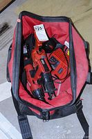 Milwaukee cordless Sawzall, cordless hammer drill, battery packs, charger, and bag inside large Milwaukee canvas bag showing tool contents and setup.
