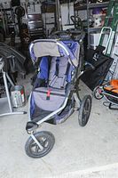Front view of B.O.B. jogging stroller showing seat, harness, and canopy in blue and gray fabric.