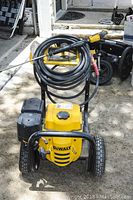 Front view of pressure washer showing DeWalt logo, engine cover and hose coiled on frame