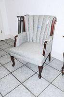 Side view of tufted back arm chair showing light green damask upholstery and cherry wood arms and legs.