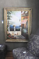 Full view of the oil painting depicting the Italian courtyard seaside scene with a flower-filled patio and water beyond, framed in an ornate gold-tone frame.