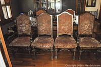 Front view of six vintage style upholstered dining chairs arranged in a row, showing floral brocade fabric and carved wooden frames.