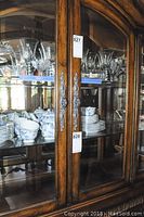Front view showing carved wood doors and glass display with tableware