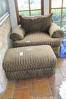 Front view of oversized armchair with matching ottoman showing green and wine striped velour upholstery