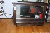 Front view of wall mirror showing full rectangular wooden frame and mirror with storage drawer below.