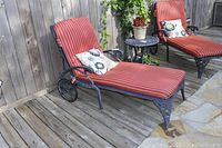 Two chaise lounges on wooden deck, each fitted with striped cushions and pillows