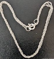 Close-up of the necklace chain and clasp on a dark background showing the intricate fine link pattern.