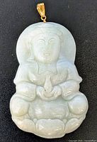 Front view of light green jadeite Buddha pendant with visible facial features, robe details and gold bail.