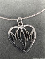 Close photo of the silver heart pendant showing the openwork design and pendant details.
