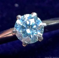 Front view of round light blue sapphire in six-prong silver setting