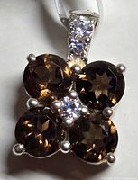 Close-up of silver pendant showing four smokey quartz stones with a central cubic zirconia and three small cubic zirconias on the bale.