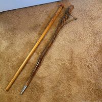 Two vintage walking sticks side-by-side on carpet, showcasing difference in wood finish and design.