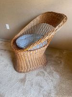 Photo showing full side view of bamboo wicker chair with curved back and a gray patterned cushion on seat.
