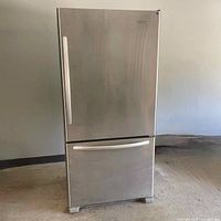 Full front view of stainless steel refrigerator with bottom freezer drawer closed