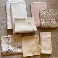 Full assortment of linens including embroidered, plain, and lace varieties on carpet background