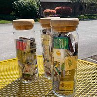 Three glass jars with wooden lids filled with various collectible matchbooks displayed outside.