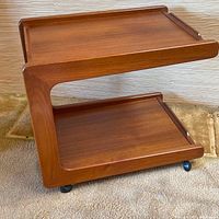 Front angle view of teak tea trolley showing both tiers and S-shaped frame