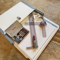 Overall view of Rotring drawing board with parallel straightedge, adjustable set squares, and Rotring pen set in beige case