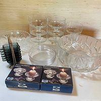 Full lot showing glass bowls, plates, square dishes stacked with metal handle, and two boxed candle holders