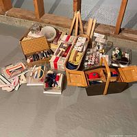Full lot overview showing multiple baskets, boxes, and containers of sewing supplies arranged on floor.
