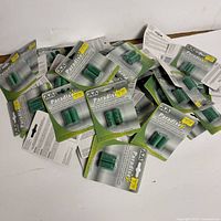 Multiple packages of Paradise brand AA rechargeable batteries in green packaging spread out on a white surface.
