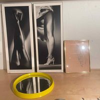 Photo showing three pieces of art by Stephen Yeates and a round yellow-framed mirror on a wooden surface.