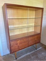 Front view of teak buffet showing sliding glass doors and tapered legs