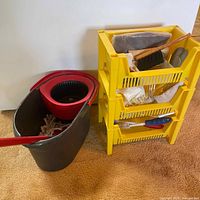 Vileda Spin Mop bucket with mop, next to yellow shelving unit with cleaning tools.