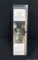 Fragrance diffuser bottle with sticks visible through transparent box, showing the liquid and label on bottle