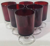 Front view of six ruby red Luminarc goblets arranged closely together, showing the rich red color and clear glass stems.