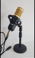 Full view of gold mesh grille On-Air microphone mounted on black stand with USB cord visible.