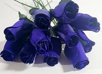 Top view showing the cluster of 12 wooden purple roses with closed petals and green leaves.