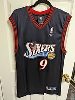 Front view of black Philadelphia 76ers basketball jersey with Andre Iguodala number 9 logo and graphics.