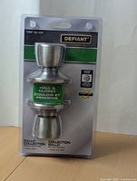 Front view of the new Defiant door knob set in original packaging with labeling showing brand, usage type, and finish.