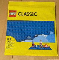 Front view of unopened LEGO Classic blue baseplate yellow package with product info and age recommendation.