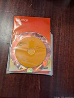 Microsoft Office Professional 2010 orange installation DVD on top of instruction booklet and product key card.