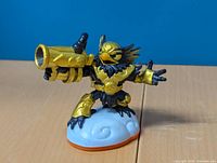 Front and side view of the golden Jet-Vac Skylanders Giants figure on a white base with orange trim.