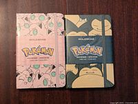 Two new sealed Moleskine Pokémon journals side by side, Jigglypuff on left pink cover, Snorlax on right blue cover.