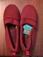 Pair of maroon women's HomeTop slippers displayed, showing top and interior with tag inside indicating memory foam cushioning.