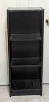 Front view of a black wooden shelving unit with three shelves.