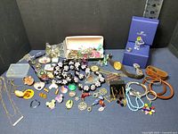 Full lot of costume jewelry, Swarovski bear in box, assorted pins, buttons, necklaces, bracelets, earrings, watches, and red gift box visible.