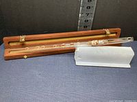 Full crystal flute laid in open wood case with green felt lining, displaying instrument length and multiple holes.