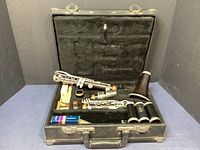 Open black hard case showing disassembled grenadilla wood clarinet and accessories